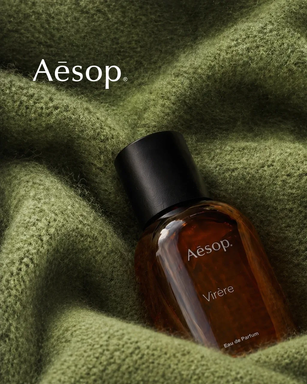 Aesop Virere key visual: the amber eau de parfum bottle on folded green cashmere, with the Aesop wordmark