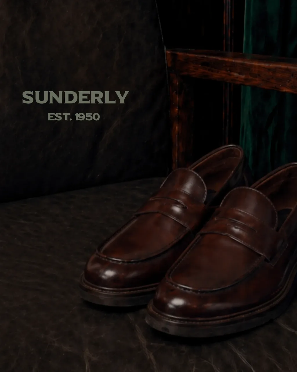 SUNDERLY key visual: brown penny loafers on a leather chair against dark wood and green velvet, with the SUNDERLY Est. 1950 lettering