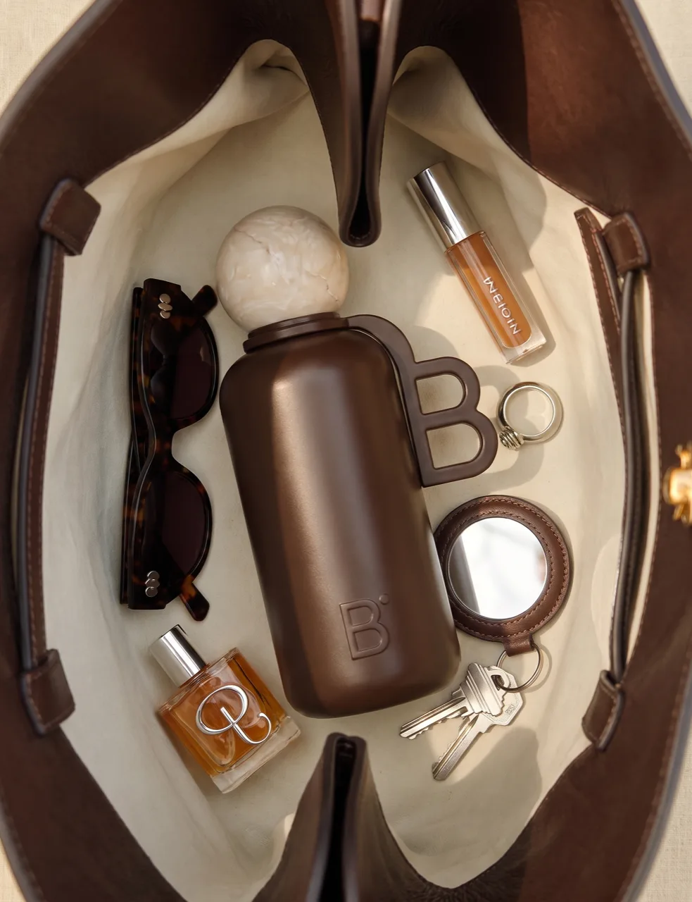 Beau product photography, insulated flask in a tote with sunglasses and perfume