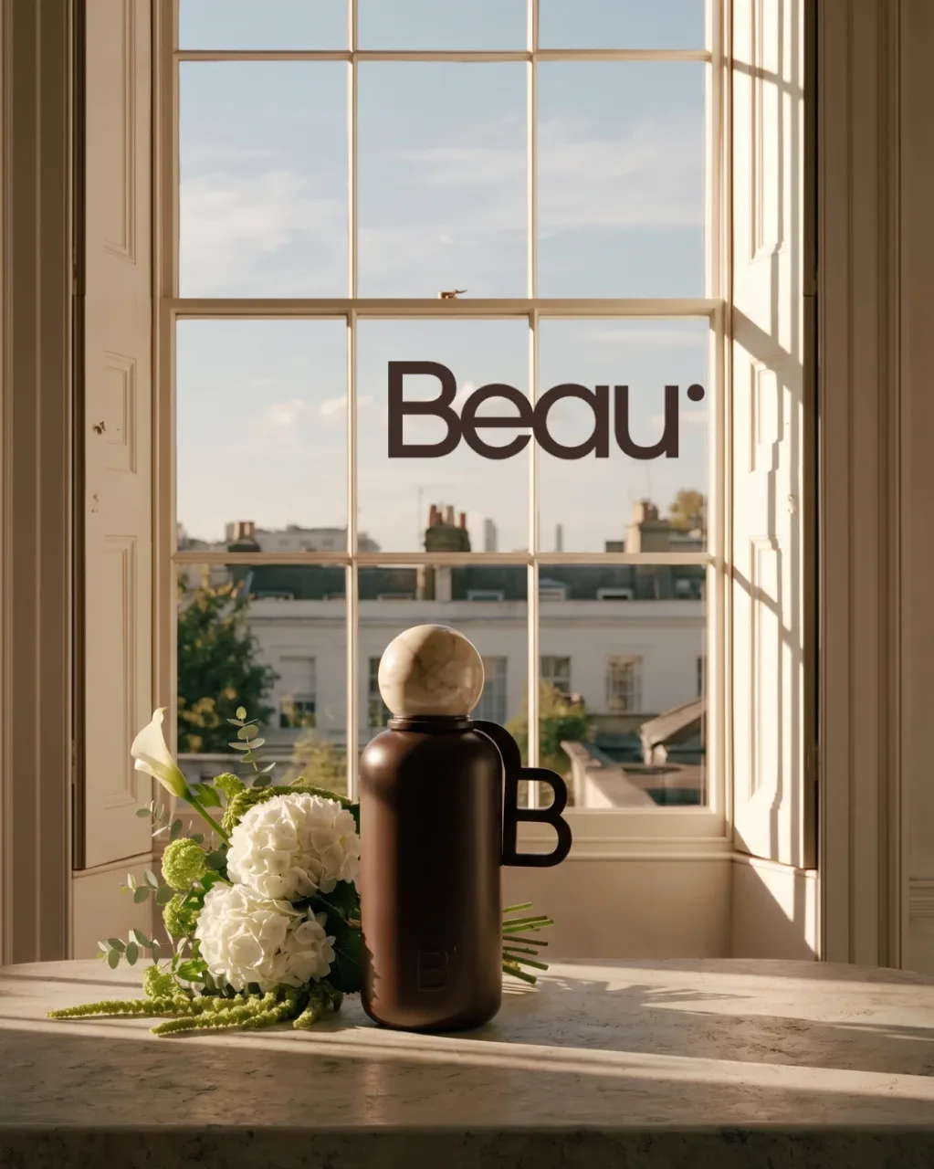 Beau key visual: the insulated bottle and white hydrangeas on a marble table by a tall window, with the Beau wordmark