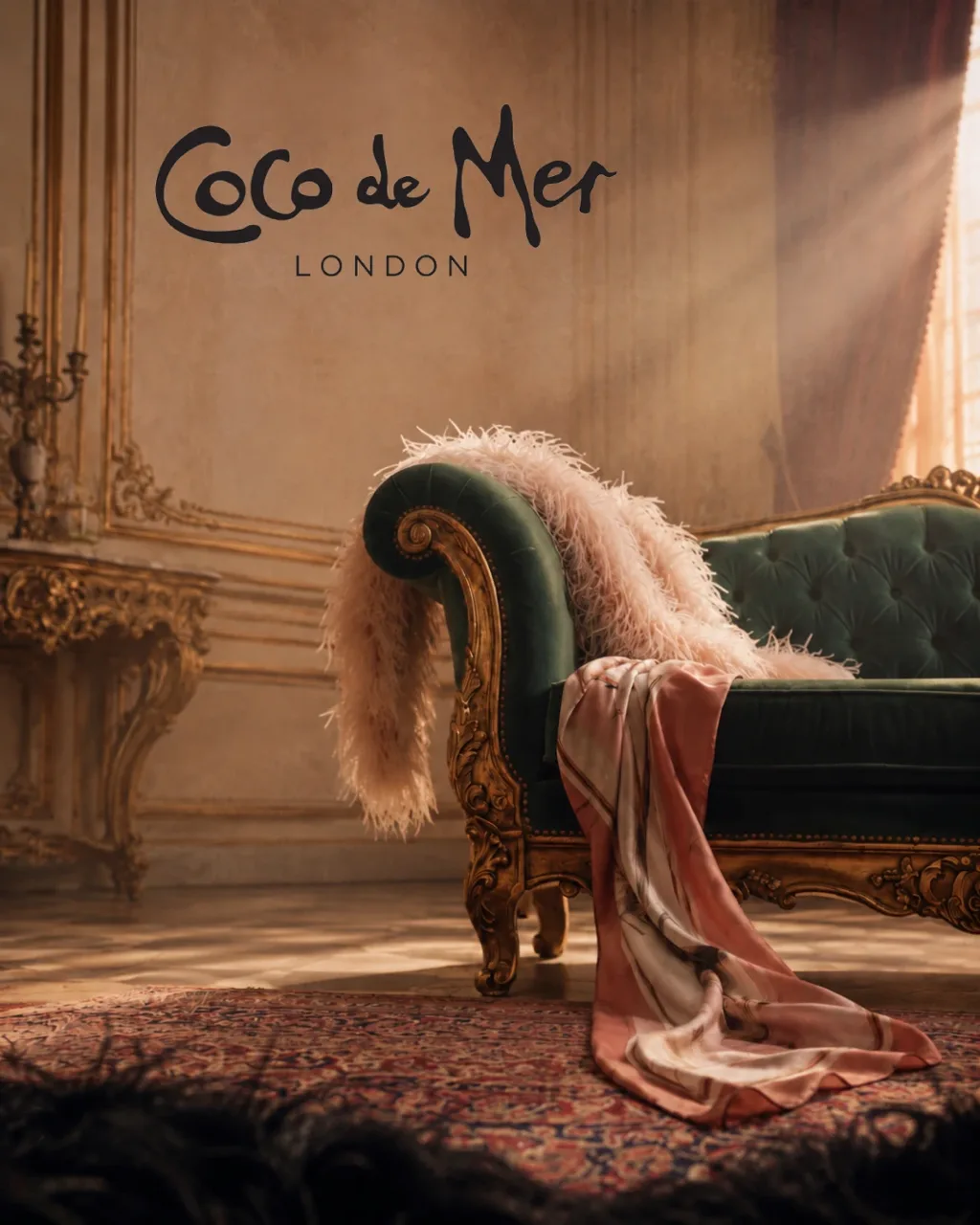 Coco de Mer key visual: a green velvet chaise with a feather boa and silk in a gilded salon, with the Coco de Mer London logo