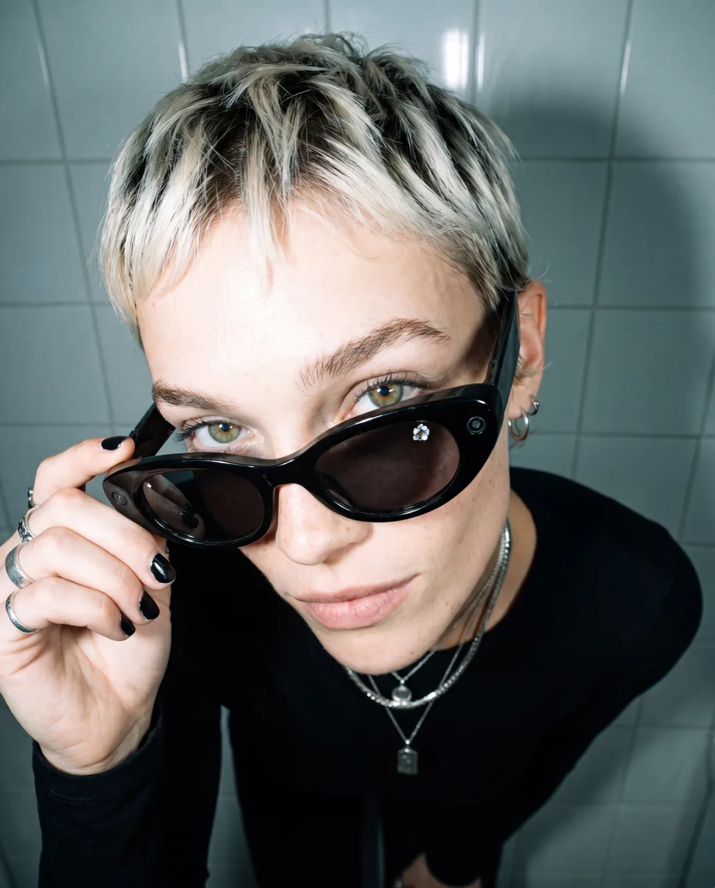 Meta smart glasses concept campaign, model lowering black sunglasses in a tiled studio