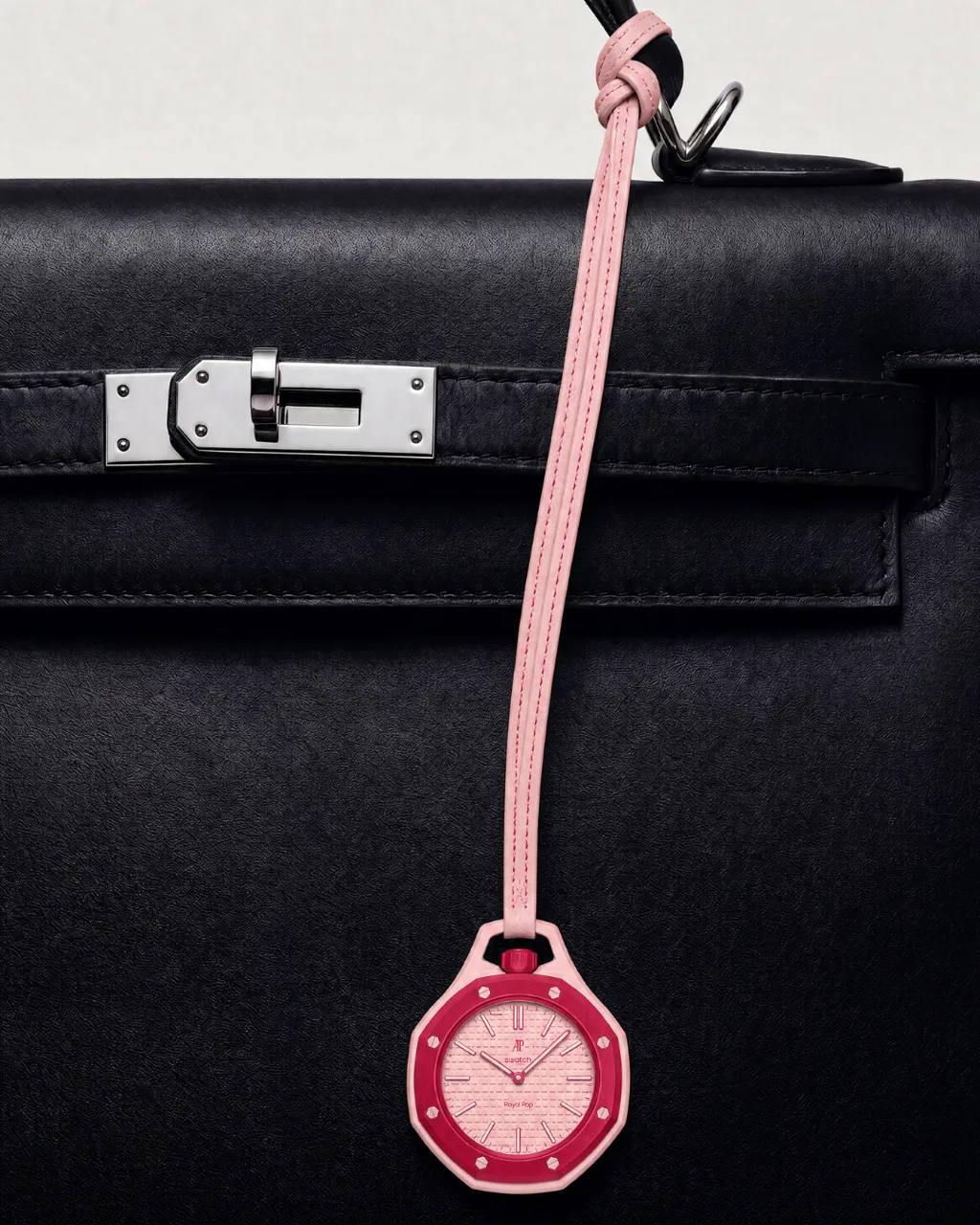 Royal POP concept campaign, pink watch charm hanging from a black leather handbag