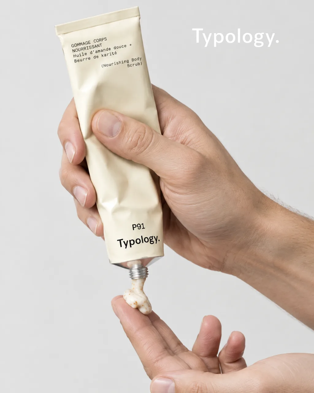 Typology P91 body scrub squeezed onto a fingertip, Typology wordmark top right